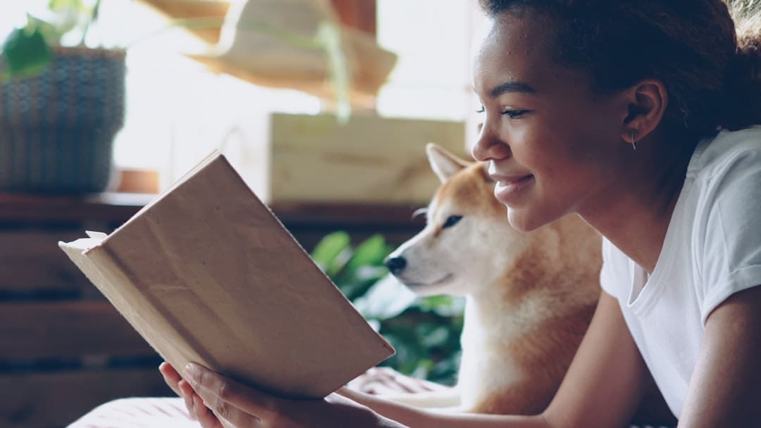 breed restrictions — A woman reads a book with her dog.